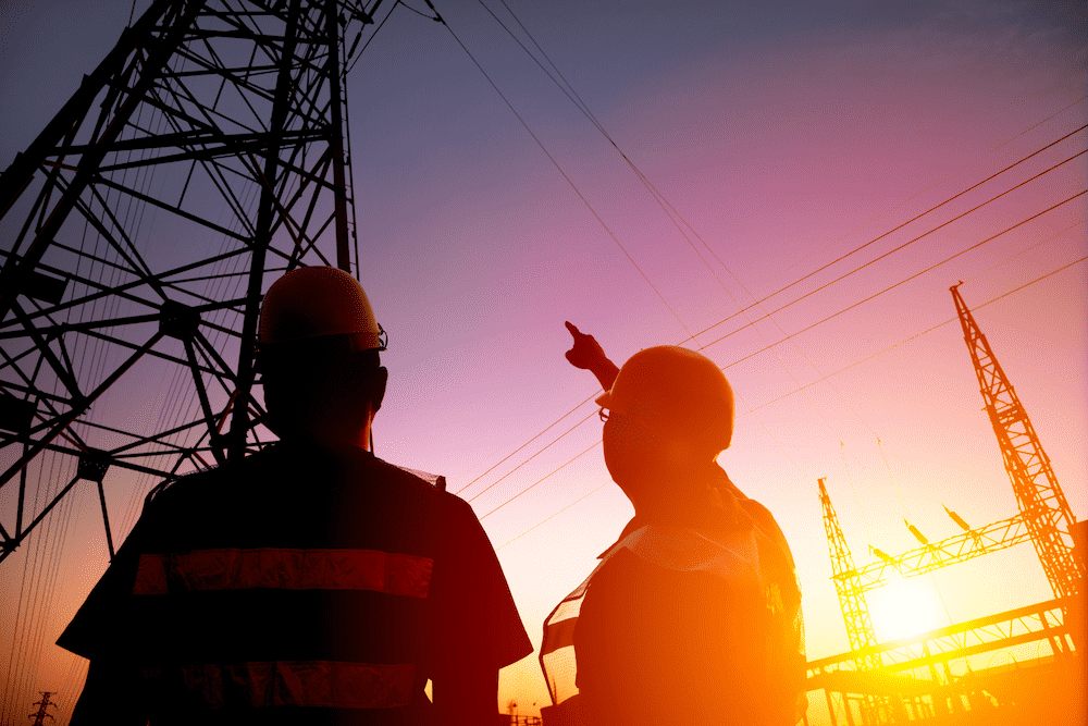 energy_tower_workers_sunset two energy workers looking at a powerline