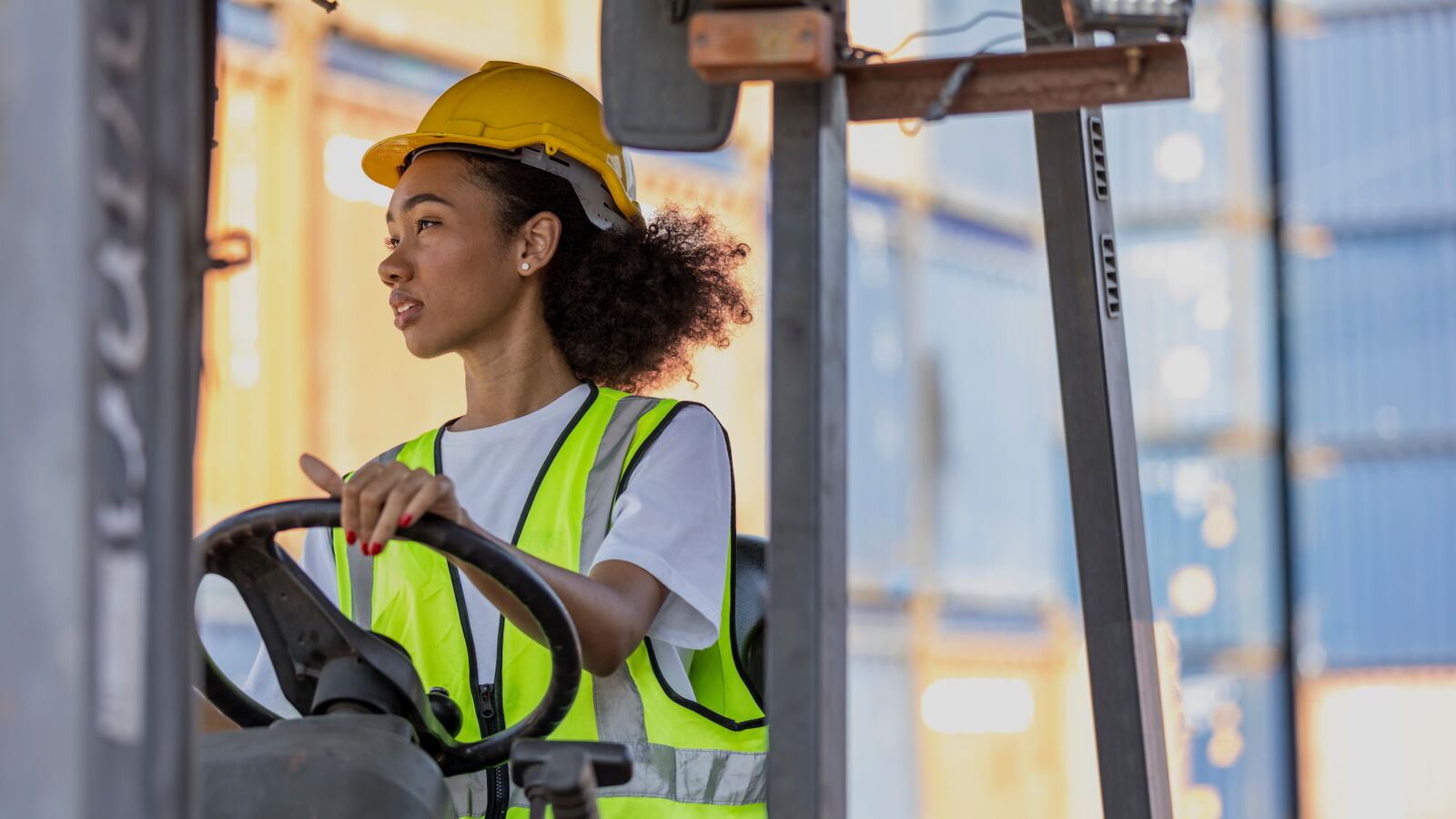 young woman operating a forklift with safety gear on