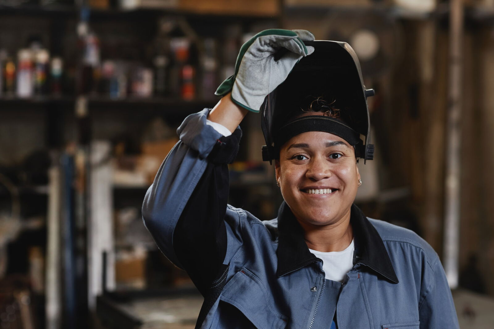 young woman opening welding mask and smiling