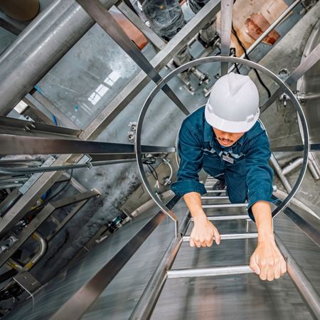 Energy industry worker climbing ladder